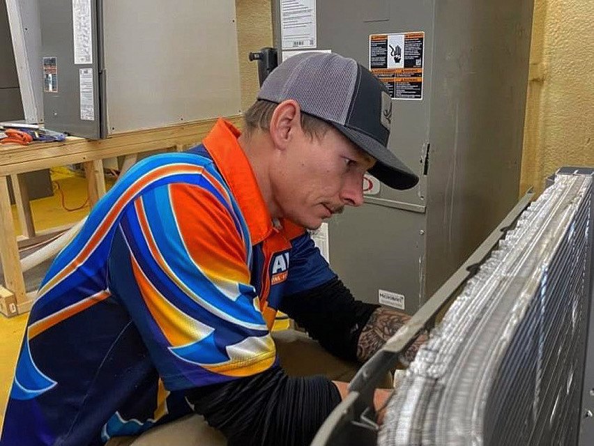 A technician working on a heating service unit.