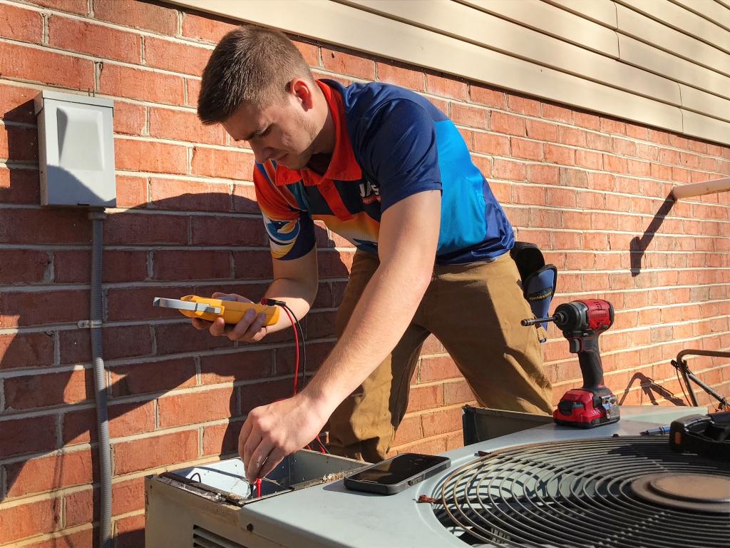 A technician is examining an HVAC unit using a multimeter