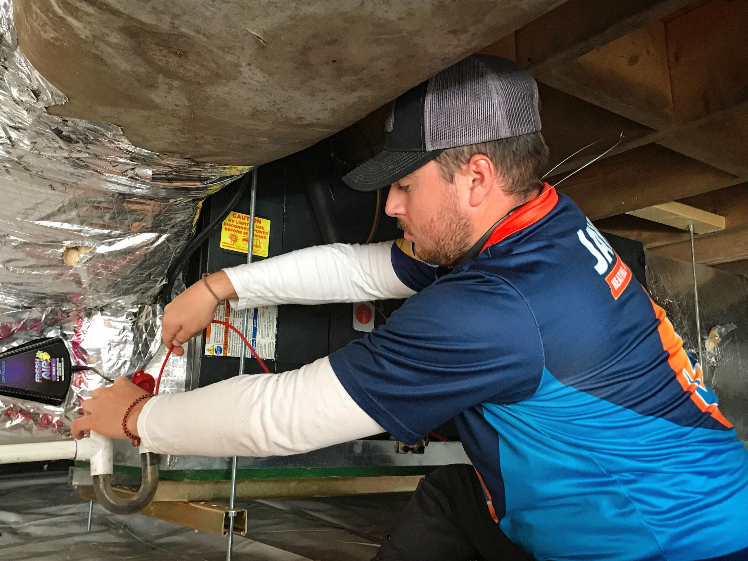 A technician making repairs on a pipe in a basement.