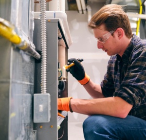worker looking into furnace with flashlight