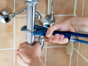 A plumber is working on a faucet in a bathroom.