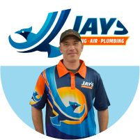 Meet the Team: A man in a multicolored uniform standing in front of a company logo for Jay's Heating, Air & Plumbing.