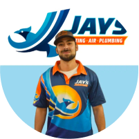 A team member in a multicolored uniform with the logo of Jay's Heating, Air & Plumbing in front of a "Meet the Team" promotional banner.
