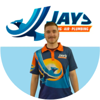 A team member in a company uniform with the Jay's Heating, Air Plumbing logo in the background.