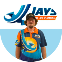 Man in a uniform with a plumbing company logo standing against a "meet the team" backdrop.