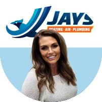 Meet the team: A woman with long brown hair and wearing a light-colored sweater stands in front of a logo for "Jays Heating - Air - Plumbing".