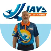 A man in a colorful Jays Heating, Air, Plumbing uniform stands smiling in front of a Jays company logo backdrop.
